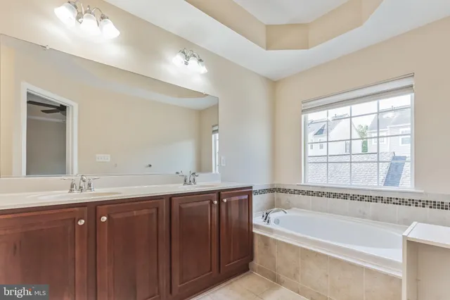 a bathroom with a bathtub a double vanity sink and mirror