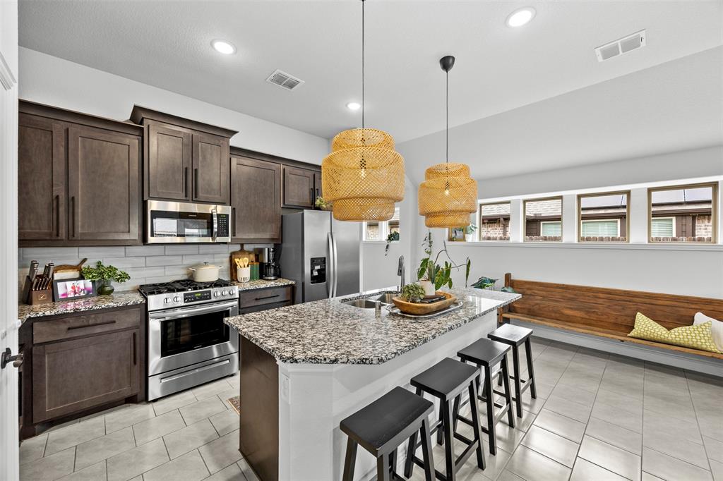 1084 Imperial Eagle Road Alvarado, TX 76009 - Photo 12 of 39 a kitchen with stainless steel appliances granite countertop a stove top oven a sink a dining table and chairs