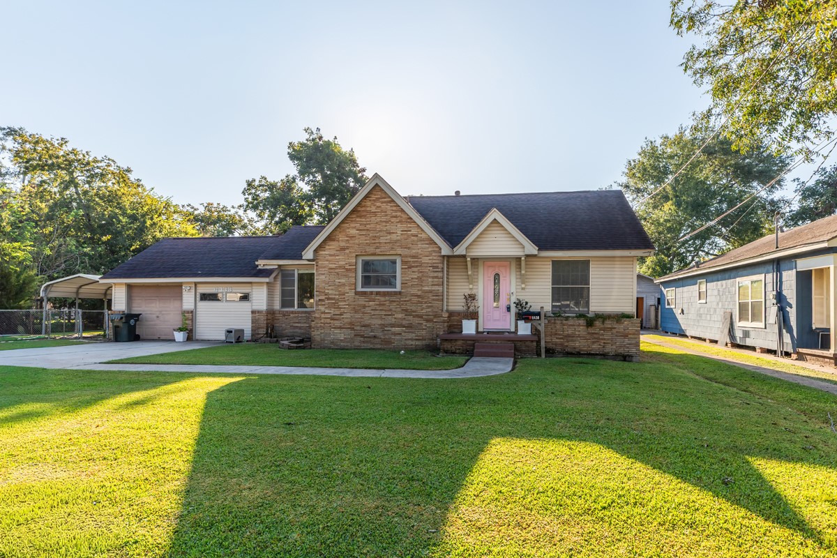 a view of a house with a big yard potted plants and large tree