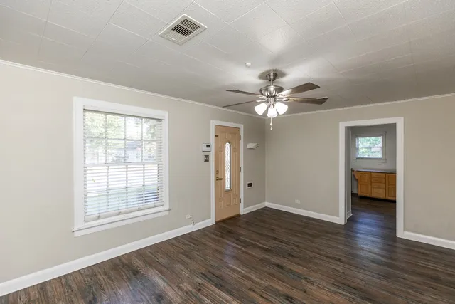a view of an empty room with wooden floor and a window