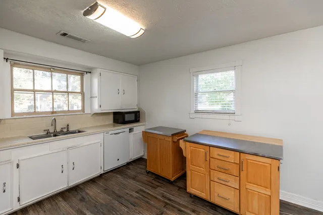 a kitchen with stainless steel appliances granite countertop white cabinets sink and window