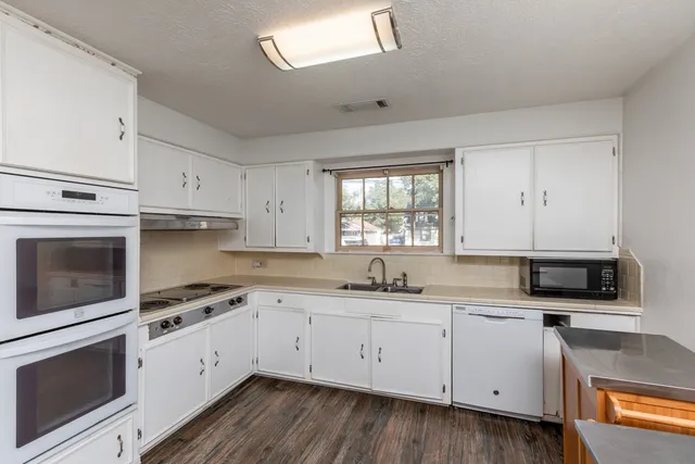 a kitchen with cabinets appliances a sink and a window