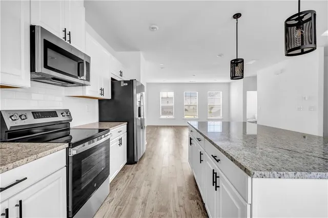 a kitchen with stainless steel appliances granite countertop a stove a sink and a refrigerator