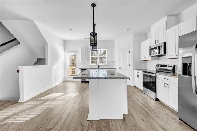a large kitchen with cabinets wooden floor and stainless steel appliances