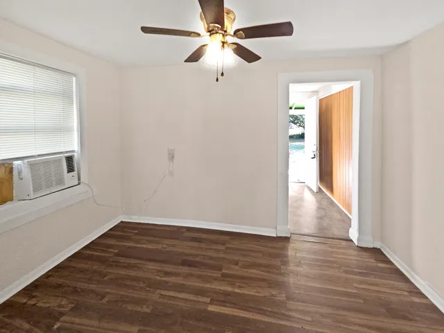 a view of an empty room with window a ceiling fan and wooden floor