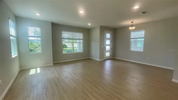 an empty room with wooden floor and windows