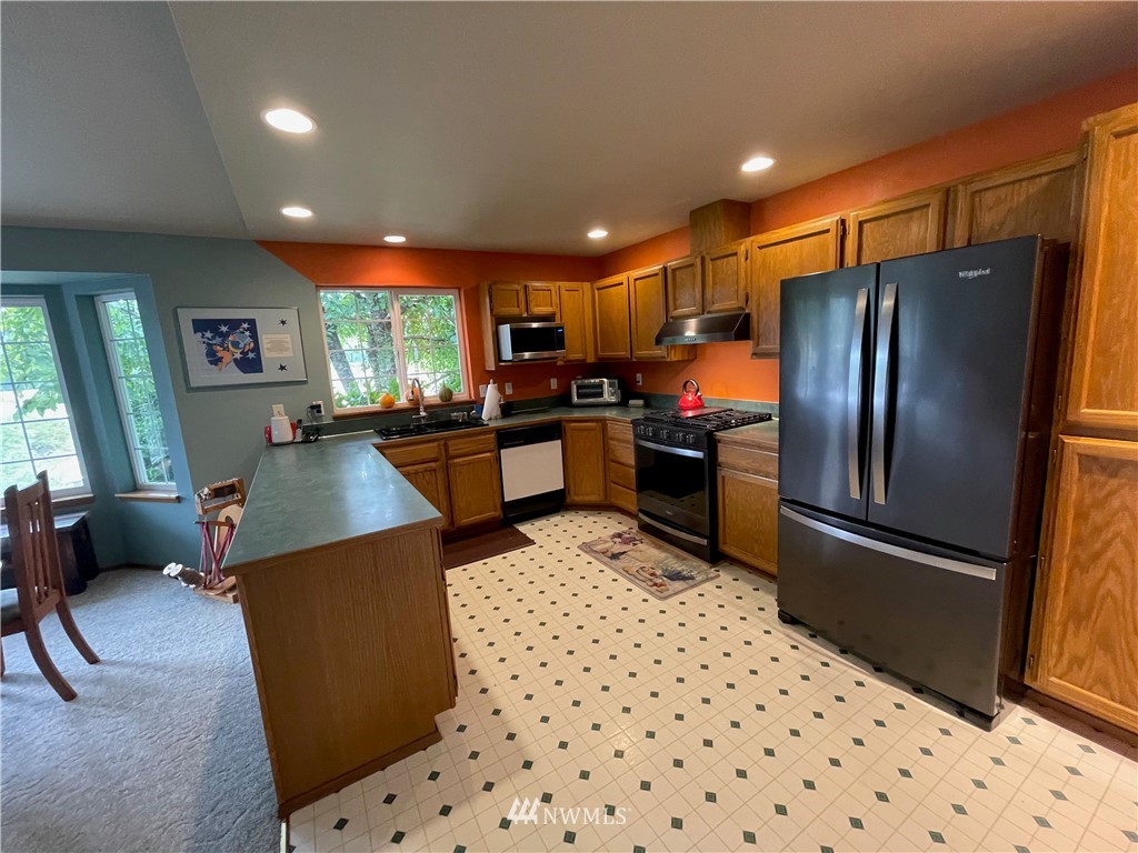 404 Independence Road Rochester, WA 98579 - Photo 28 of 40 a kitchen with stainless steel appliances kitchen island granite countertop dining table chair sink and refrigerator