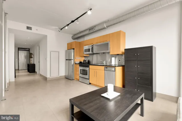 a kitchen with a refrigerator a stove and white cabinets with wooden floor