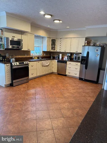 a large kitchen with stainless steel appliances granite countertop a stove top oven a sink a counter space and cabinets