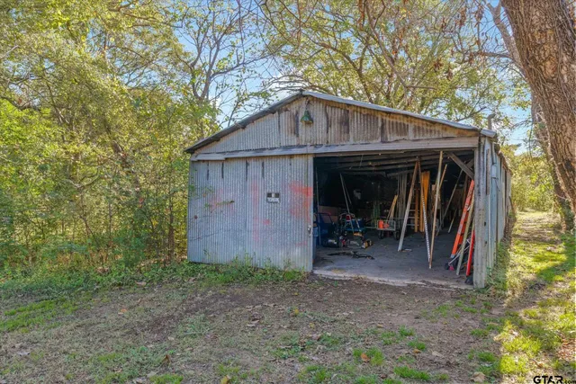 a view of a barn in the backyard with large trees