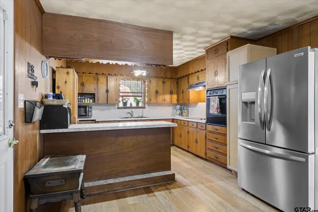 a kitchen with stainless steel appliances granite countertop a refrigerator a stove and a sink with wooden floors