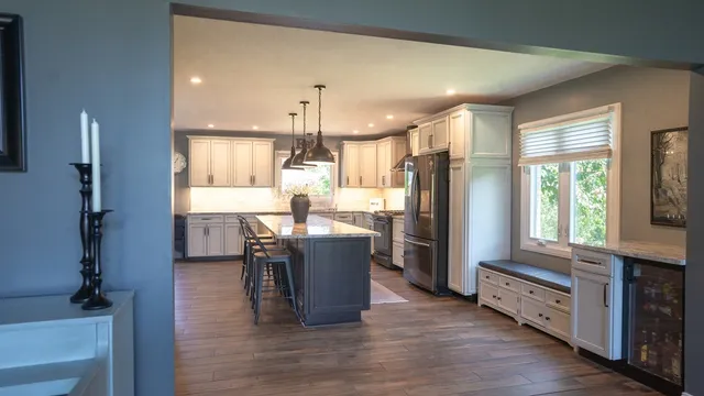 a kitchen with stainless steel appliances granite countertop wooden floors a stove a center island and chairs