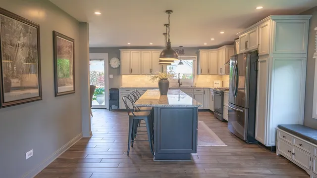 a kitchen with stainless steel appliances granite countertop a sink a stove a refrigerator and chairs