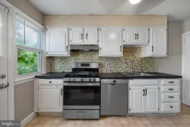 a kitchen with white cabinets and appliances