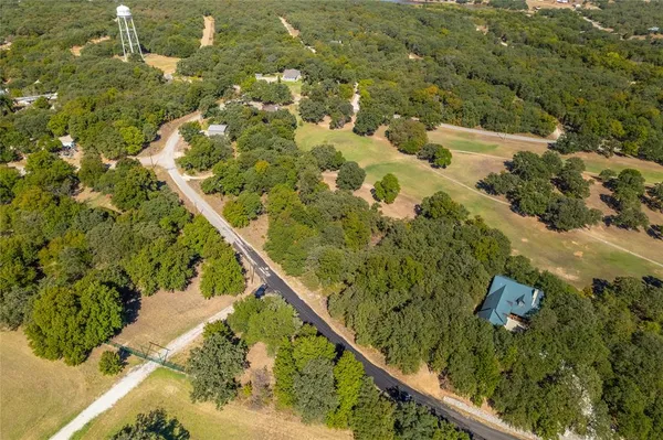 an aerial view of residential houses with outdoor space and trees