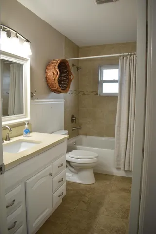 a bathroom with a toilet a sink a mirror a window and vanity