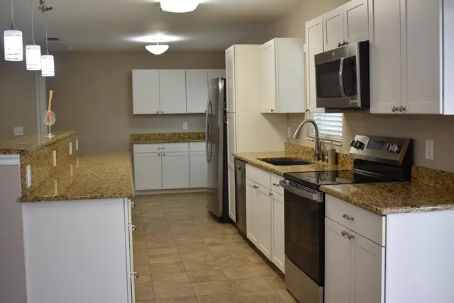 a kitchen with granite countertop cabinets stainless steel appliances and a counter space