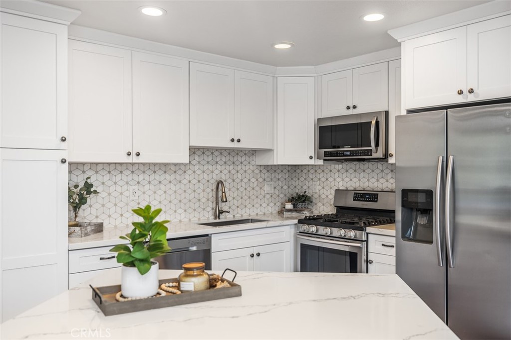 a kitchen with stainless steel appliances white cabinets a stove a microwave and a refrigerator