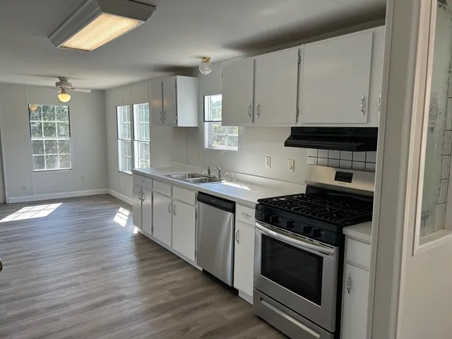 a kitchen with stainless steel appliances granite countertop a stove and a wooden floors