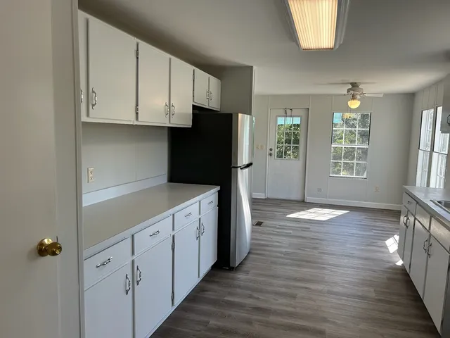 a kitchen with white cabinets and wooden floor