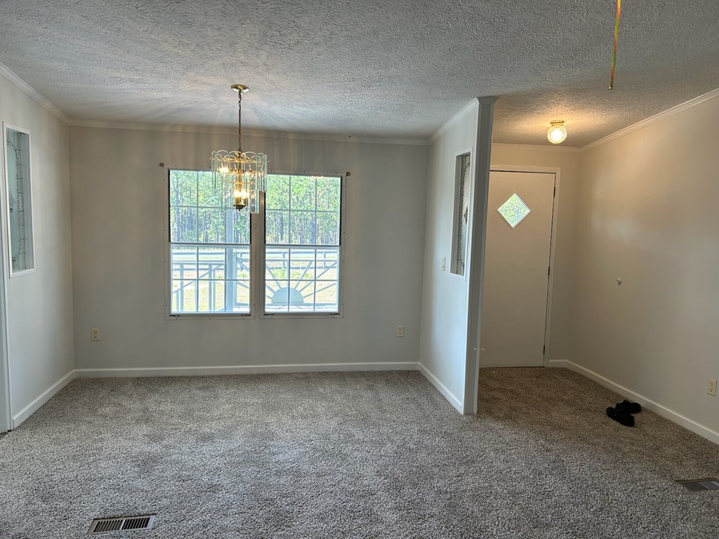 1300 Dr Brooks Road Box Springs, GA 31801 - Photo 8 of 16 an empty room with chandelier fan and windows