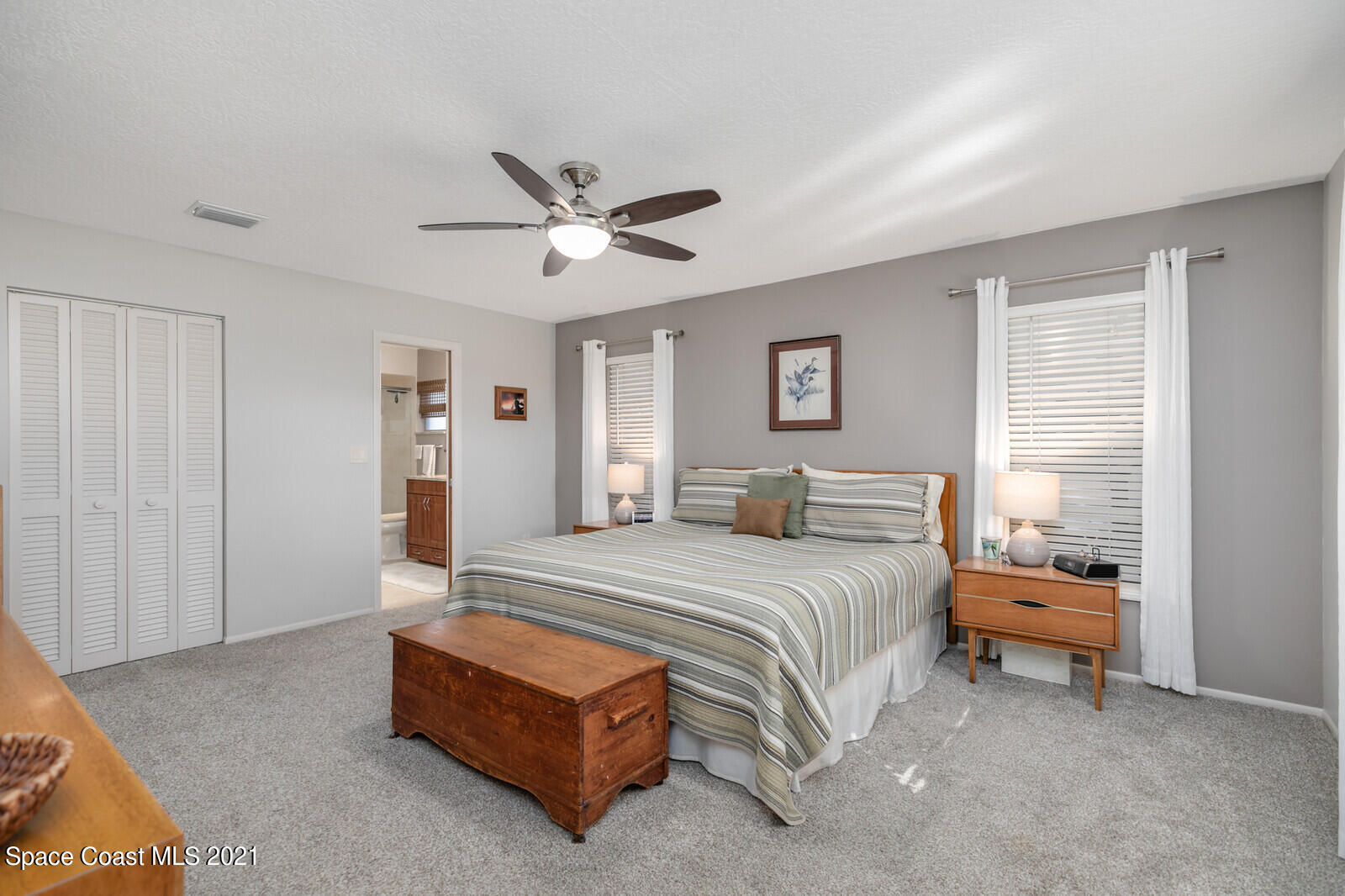 791 Montclair Road Northeast Palm Bay, FL 32905 - Photo 33 of 69 a spacious bedroom with a bed and a chandelier