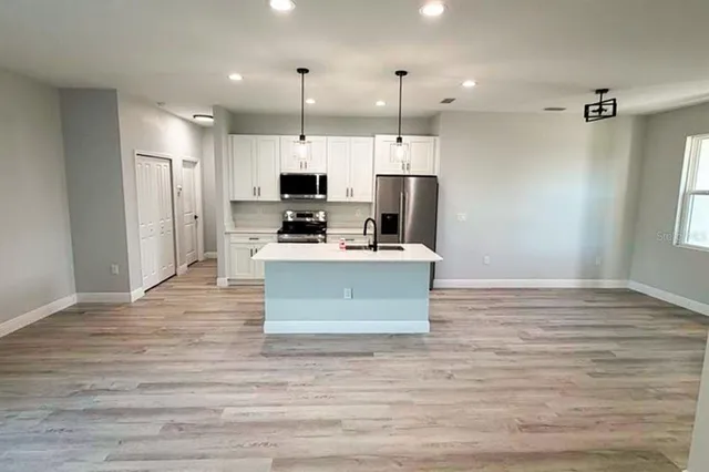 a view of kitchen with stainless steel appliances granite countertop a stove top oven a sink dishwasher and a refrigerator with wooden floor