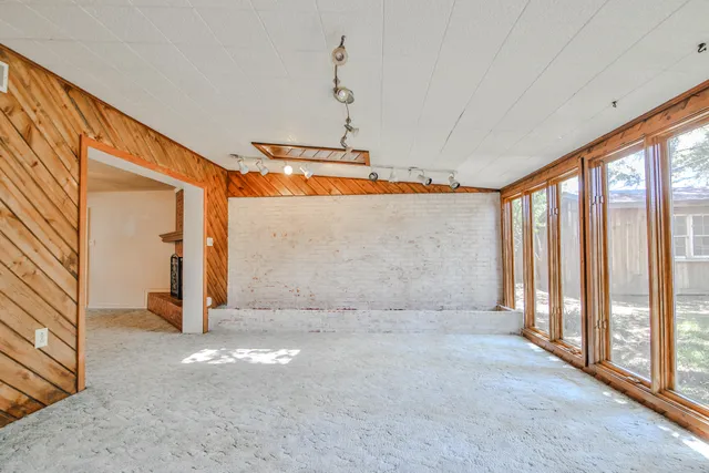 an empty room with a ceiling fan and window