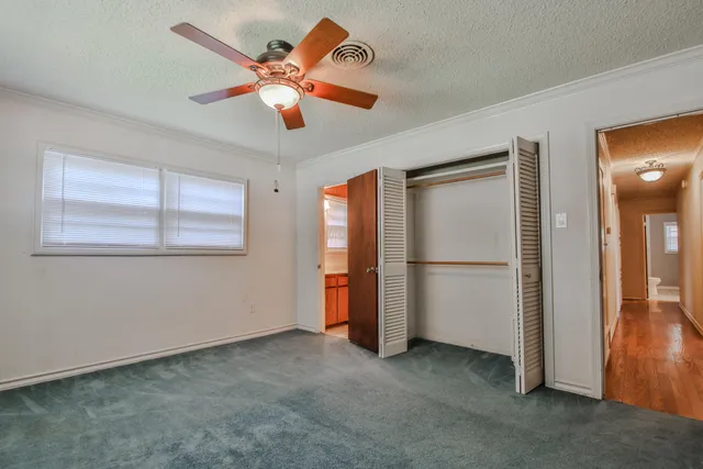 an empty room with closet and a ceiling fan