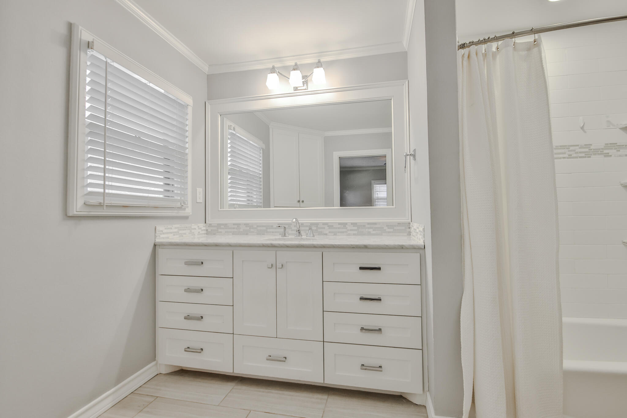 4315 47th Street Lubbock, TX 79413 - Photo 28 of 37 a bathroom with a sink a mirror and a window