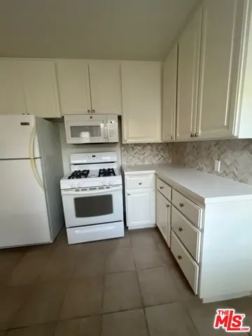 a kitchen with cabinets appliances and white cabinets