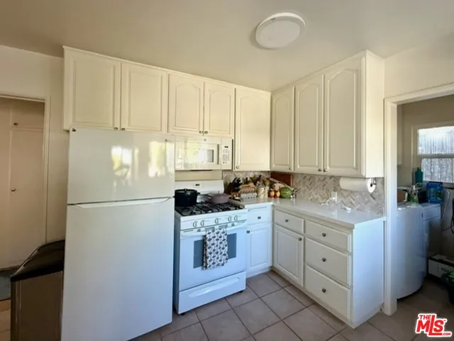 a kitchen with white cabinets and white appliances