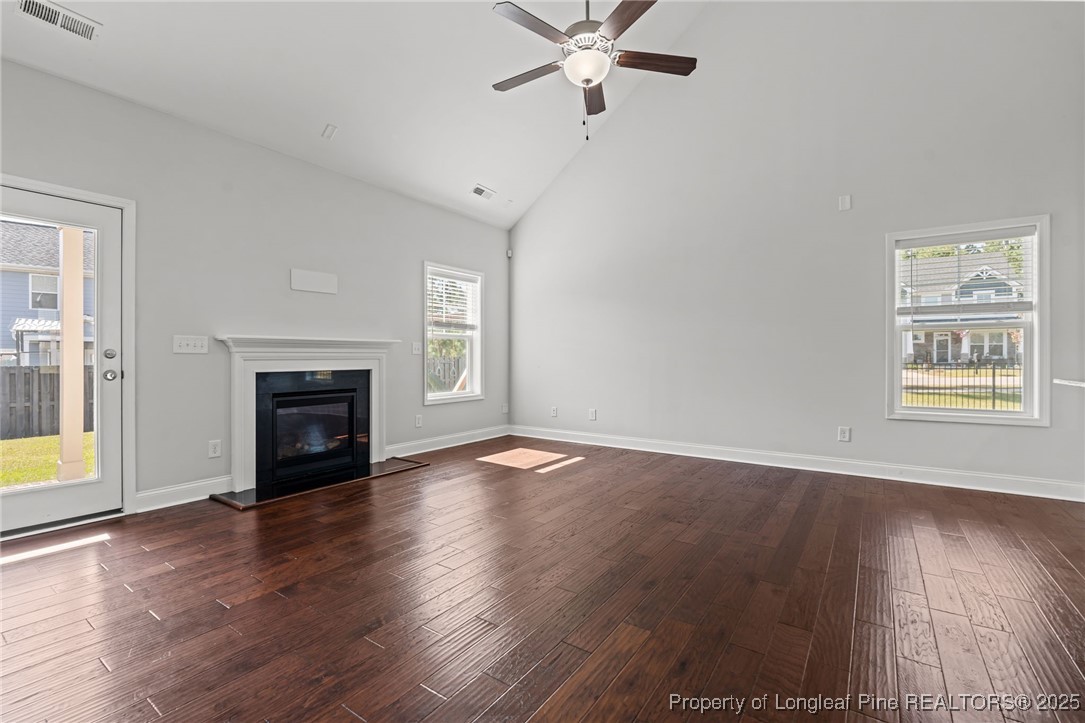 335 Parrish Lane Carthage, NC 28327 - Photo 22 of 50 an empty room with wooden floor a fireplace and windows