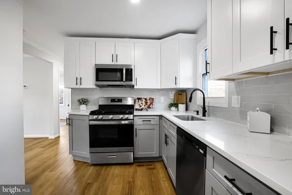 a kitchen with granite countertop a stove a sink and a microwave