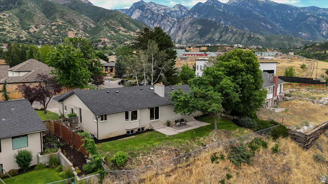 8760 Rustler Road Cottonwood Heights, UT 84093 - Photo 3 of 57 Rear exterior with a stone patio, manicured lawn, and mature trees