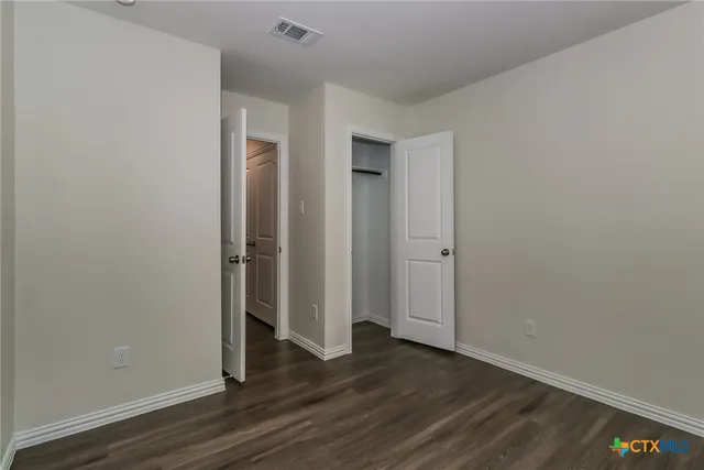 an empty room with wooden floor and closet