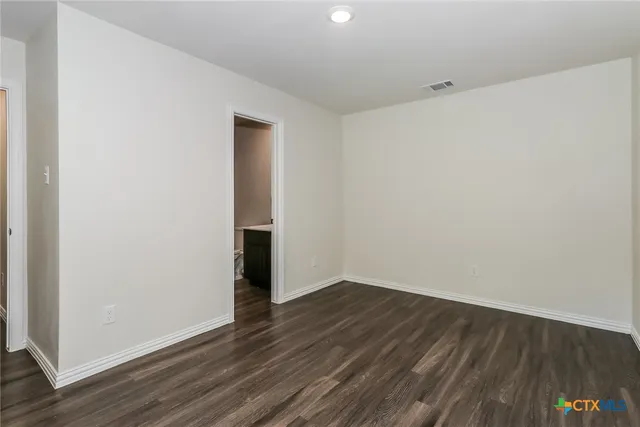 a view of an empty room with wooden floor and closet