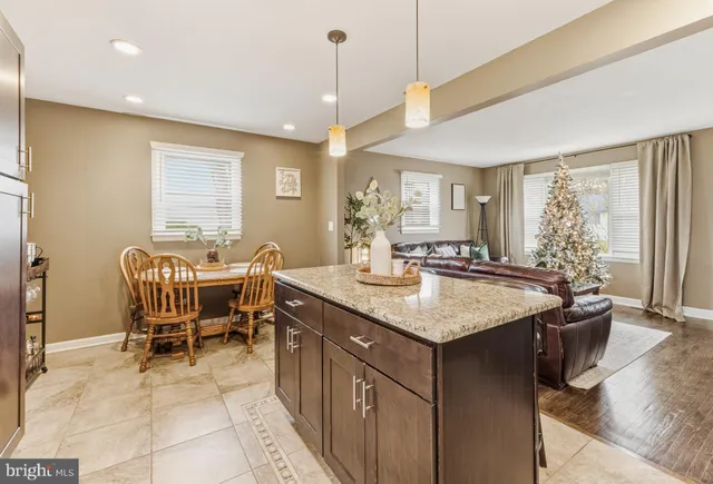 a dining hall with stainless steel appliances granite countertop a sink a dining table and chairs with wooden floor