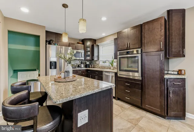 a kitchen with stainless steel appliances granite countertop a sink refrigerator and cabinets