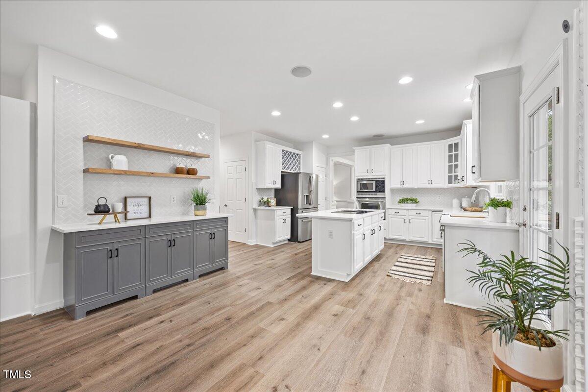 4 Pickard Place Durham, NC 27703 - Photo 13 of 80 a large kitchen with kitchen island a stove a sink a refrigerator and white cabinets with wooden floor