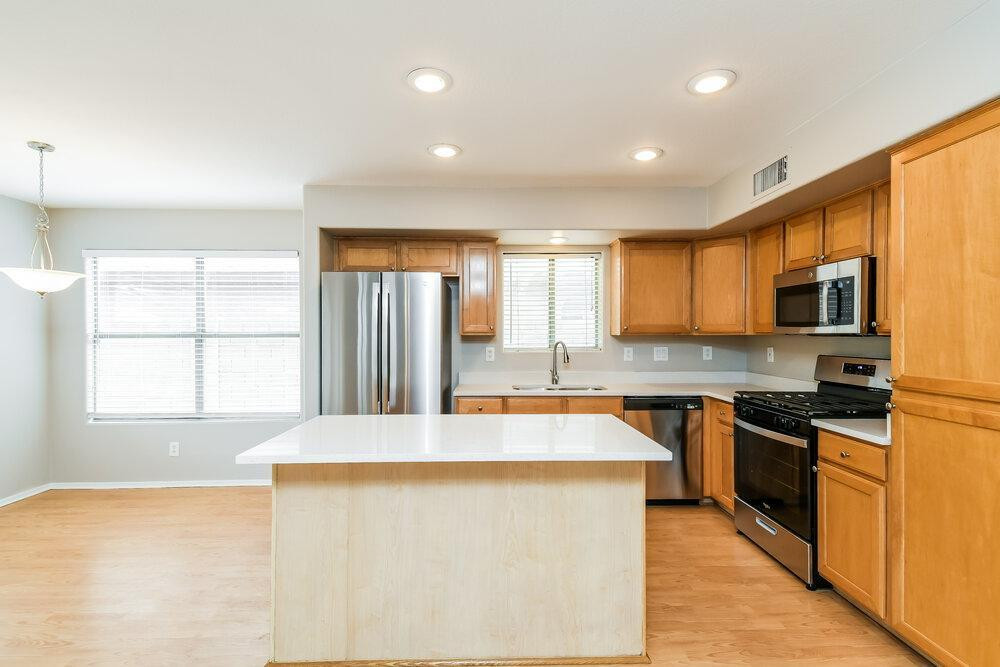 1766 East Tyson Street Gilbert, AZ 85295 - Photo 3 of 17 a large kitchen with stainless steel appliances granite countertop a stove a sink a refrigerator and white cabinets with wooden floor