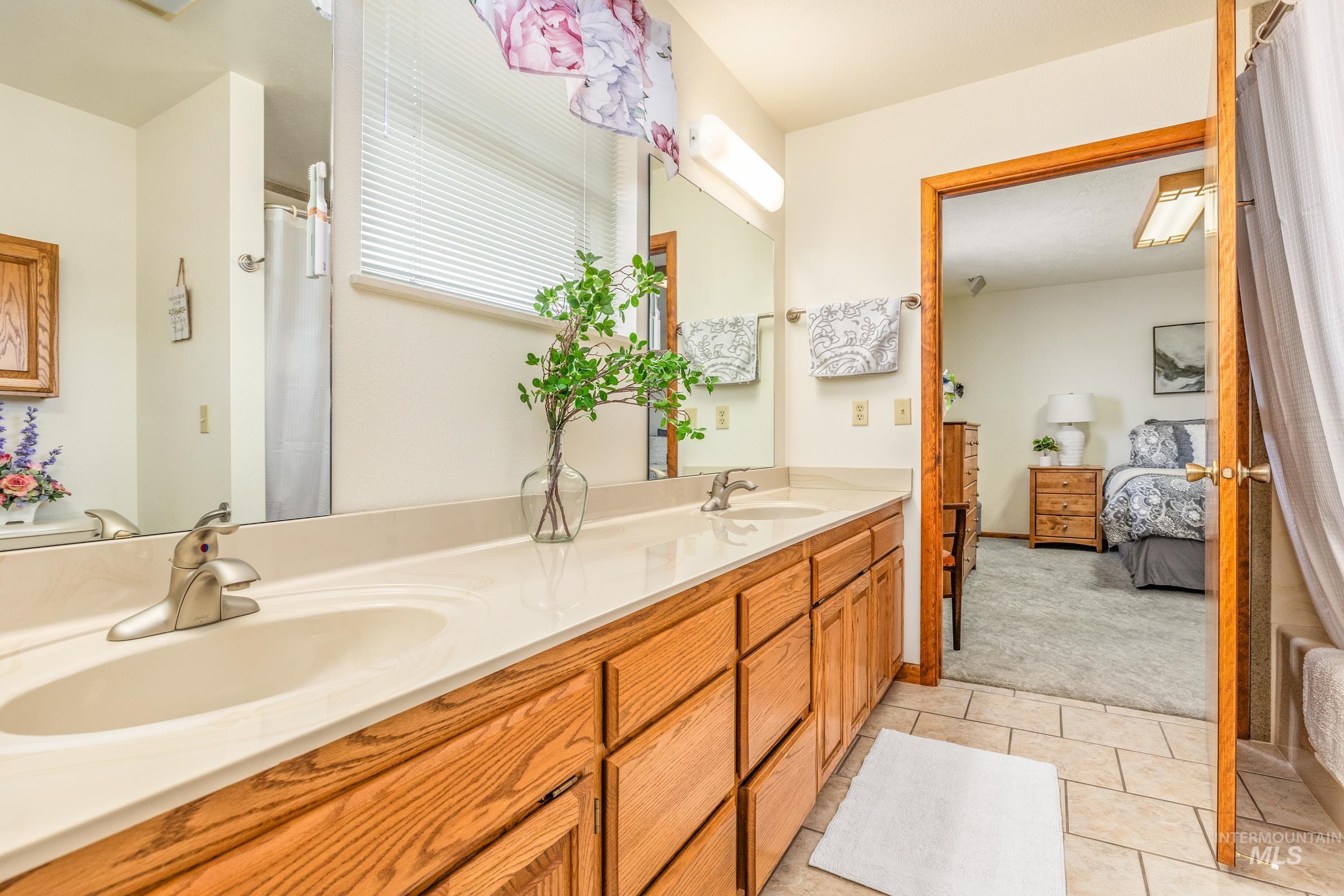 10514 Airpark Loop Road Melba, ID 83641 - Photo 14 of 47 Ensuite bathroom featuring double vanity, light carpet, a shower with curtain, and light tile patterned flooring