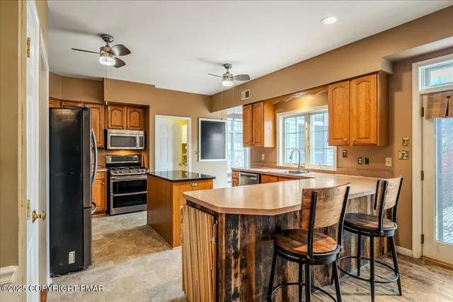 a large kitchen with stainless steel appliances a large counter top a refrigerator a sink a stove and cabinets