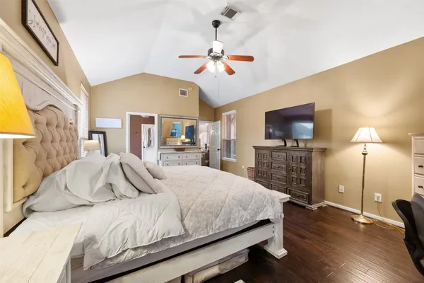 a bedroom with a large bed a flat tv screen and a chandelier