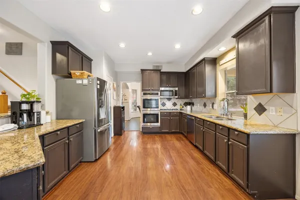 a large kitchen with stainless steel appliances granite countertop a stove refrigerator and cabinets