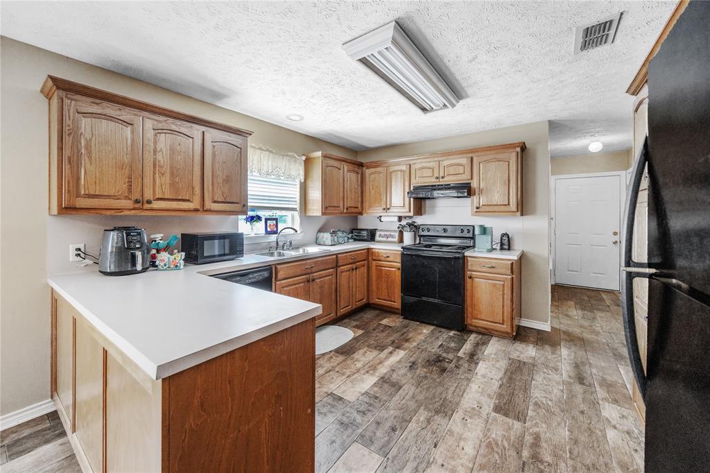 2895 County Road 118 Overton, TX 75684 - Photo 23 of 40 a kitchen with stainless steel appliances granite countertop a stove top oven a sink a refrigerator and white cabinets