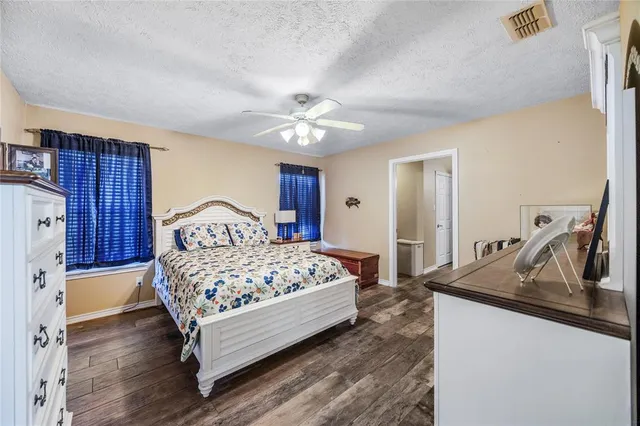 a bedroom with a bed and a dresser with wooden floor