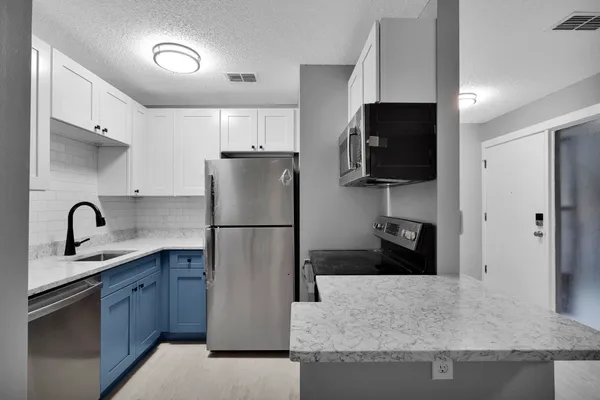 a kitchen with a sink a refrigerator and a stove top oven