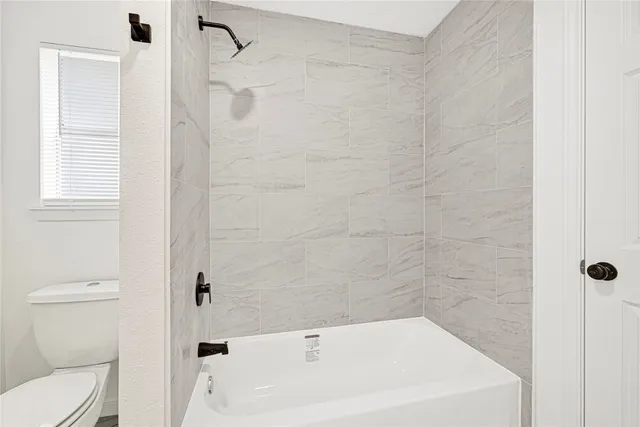 a bathroom with a white bath tub a toilet and a shower