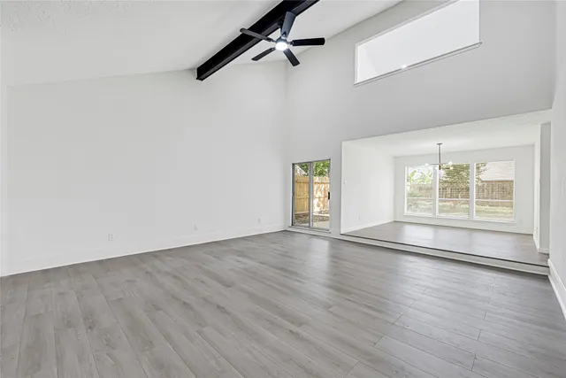 an empty room with wooden floor cabinet and windows